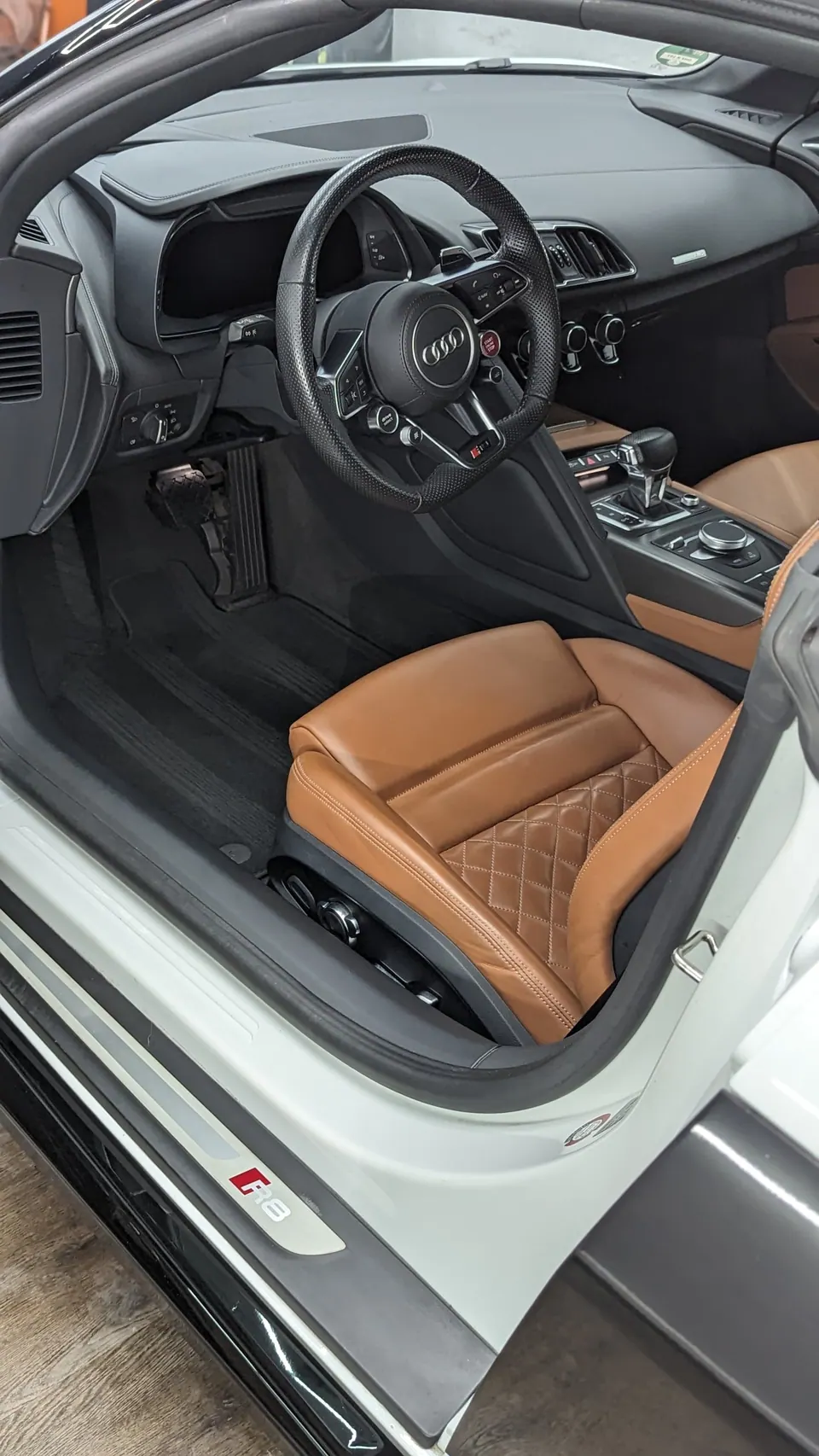 Hände mit schwarzen Handschuhen halten Politurprodukt und Applikator über rotem Auto